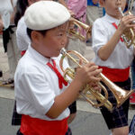 A young trumpeter working hard on a humid day