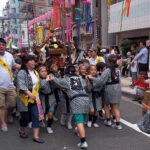 A group of kids carry a mikoshi (shrine float) down the parade route.