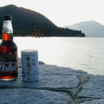 Enjoying a Hiroshima Cola and Maboroshi Sake as the sun sets behind the Great Torii on Miyajima. The unique natural cola is made with hassaku, a fruit similar to an orange or grapefruit.