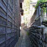 A narrow walkway between buildings leading to the trail up to Satta Pass