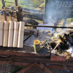 A woman at a roadside stand making krolan, a traditional Cambodian food made from sticky rice mixed with coconut, palm sugar and soybeans. It’s stuffed into a piece of bamboo stalk, sealed off with banana leaves and roasted over a hot charcoal fire.