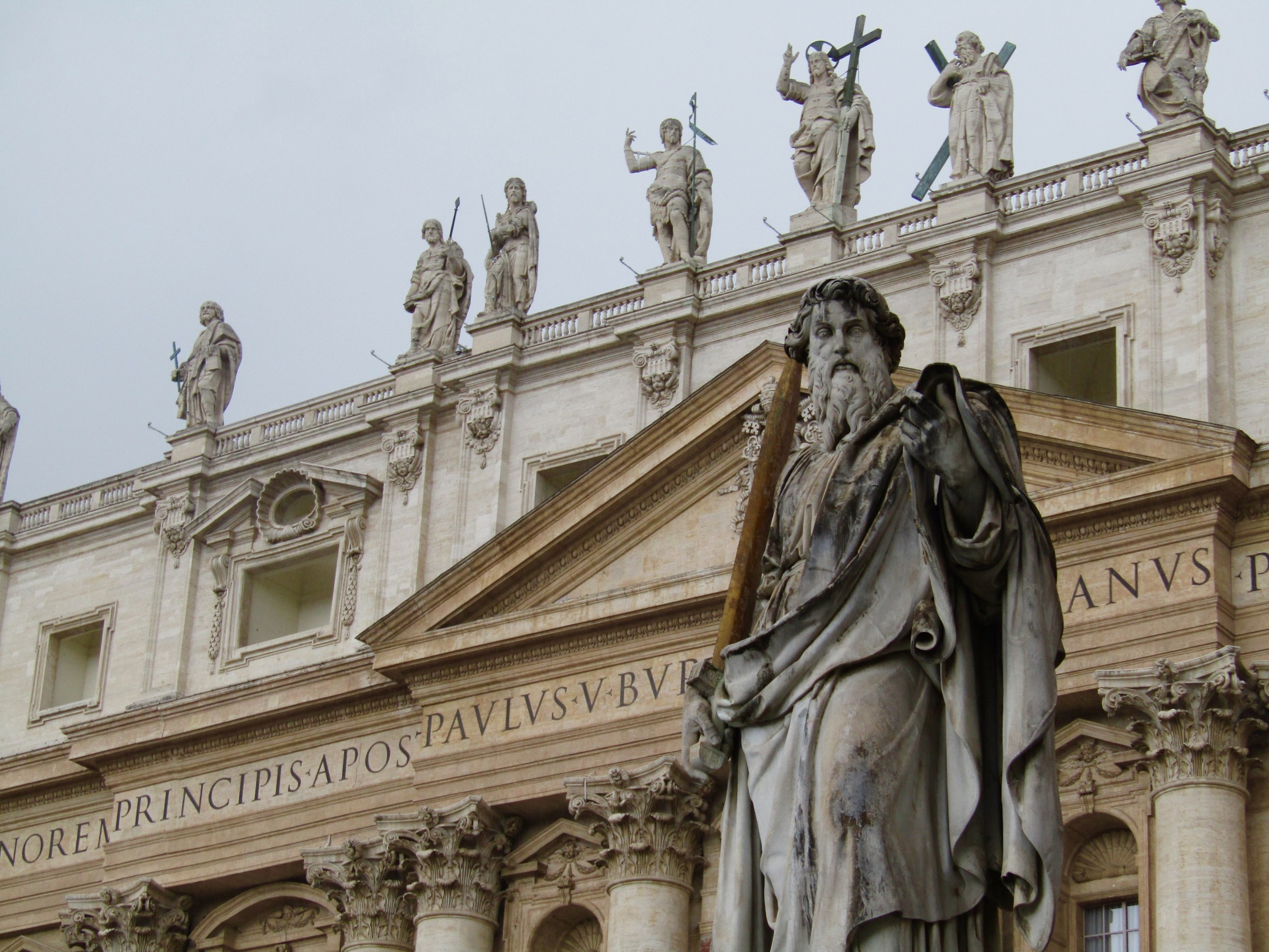 A statue of St. Paul at St. Peter's Basilica. Jesus is front and center atop the facade flanked by St. John the Baptist and St. James the Greater to the right and St. Andrew and St. John the Apostle to the left.