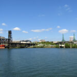 Looking east over the Willamette River toward the Steel Bridge, Moda Center—home to the NBA's Portland Trail Blazers—and the glass towers of the Oregon Convention Center.