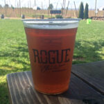 The Rogue Farms 8-Hop IPA at the farm in Independence, Ore. Rows of Rogue's proprietary hops can be seen growing in the background.