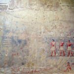 The large figure is Idut standing in a boat. To the right, young scribes are depicted.