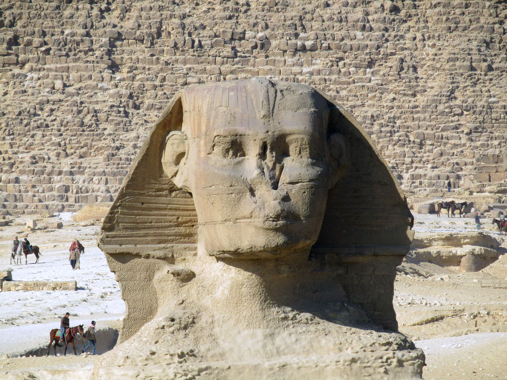 Close up of the Sphinx's face with a pharaoh's headdress and missing nose. Look how tiny the horseback riders are in comparison!